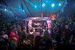Musicians at Lindisfarne Festival under a small stage lit awning inside a marquee tent.